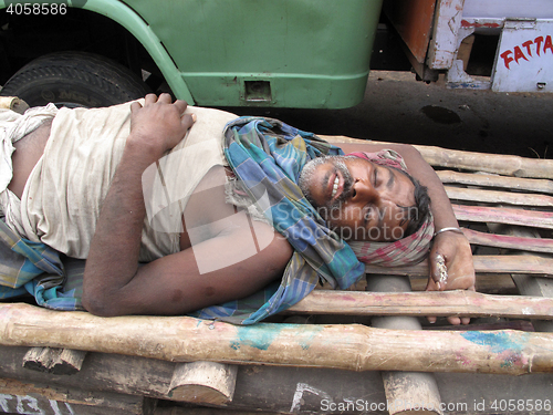 Image of Indian man asleep waiting for customers to transport their cargo