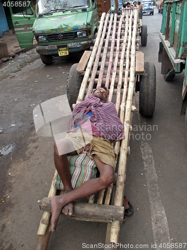 Image of Indian man asleep waiting for customers to transport their cargo