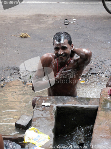 Image of Streets of Kolkata. Indian people wash themselves on a street