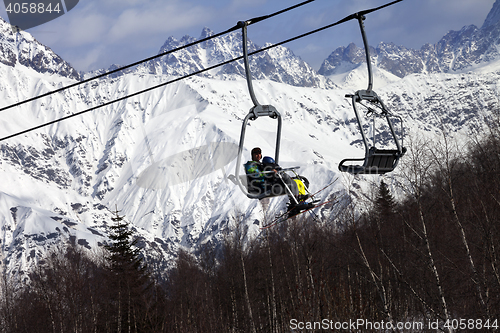 Image of Skiers on ski-lift and snow mountains at winter sun day