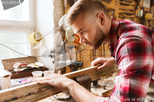 Image of carpenter working with wood plank at workshop