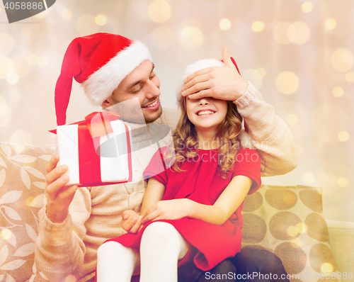 Image of smiling father surprises daughter with gift box