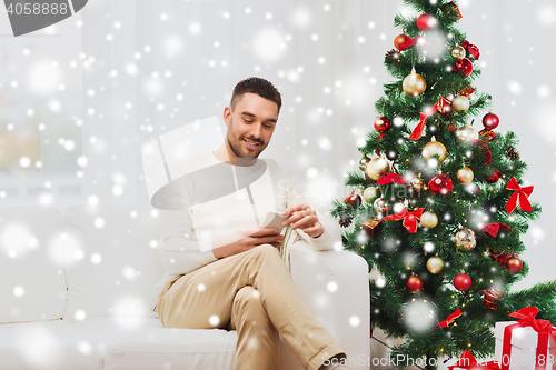 Image of smiling man with smartphone at home for christmas