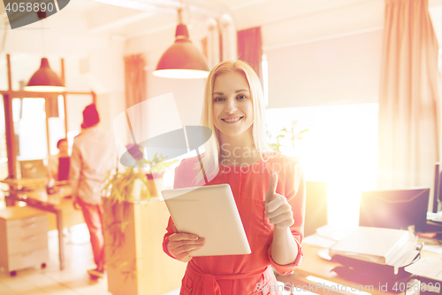 Image of woman with tablet pc showing thumbs up at office
