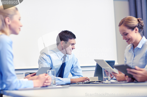 Image of smiling business people with tablet pc in office