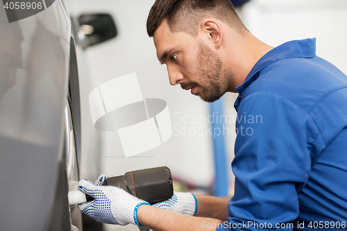 Image of mechanic with screwdriver changing car tire