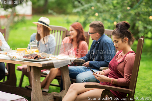 Image of woman with smartphone and friends at summer party