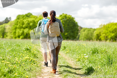 Image of happy couple with backpacks hiking outdoors