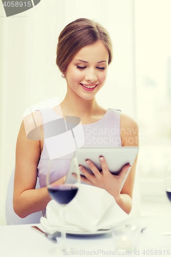 Image of smiling woman with tablet pc computer at resturant