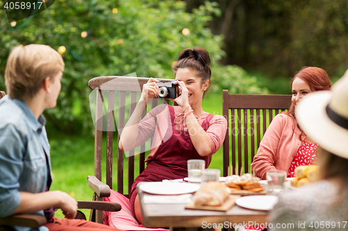 Image of friends photographing with camera at summer party