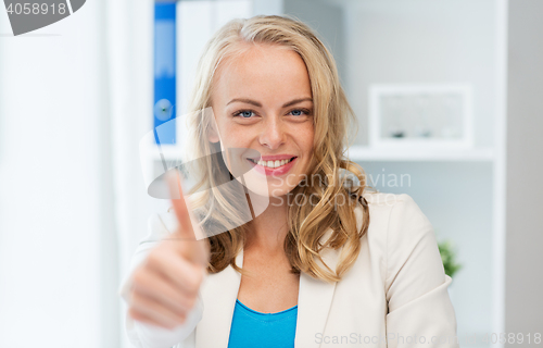 Image of happy businesswoman showing thumbs up at office