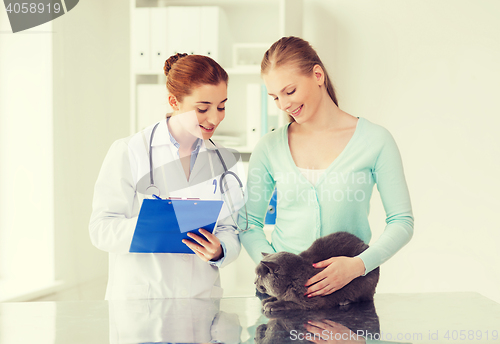 Image of happy woman with cat and doctor at vet clinic