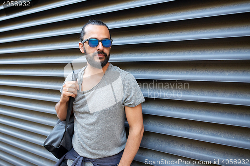 Image of man with backpack standing at city street wall