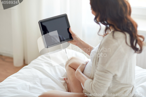 Image of close up of pregnant woman with tablet pc at home