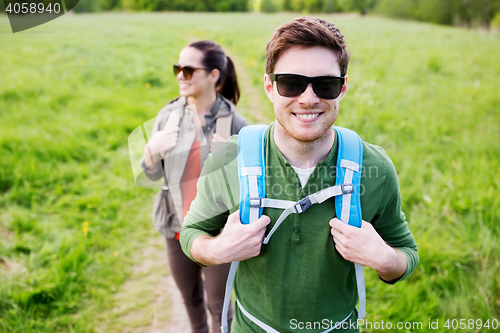 Image of happy couple with backpacks hiking outdoors