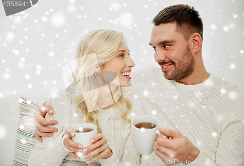 Image of happy couple with cups drinking tea at home