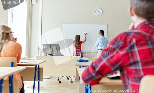 Image of teacher and student writing on board at school