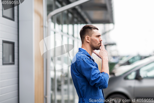 Image of auto mechanic smoking cigarette at car workshop