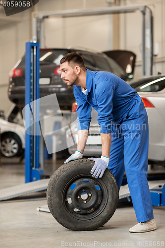 Image of mechanic with wheel tire at car workshop