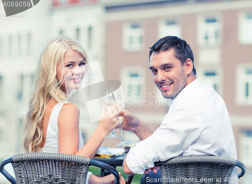 Image of smiling couple drinking wine in cafe