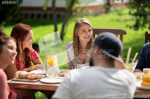 Image of happy friends having dinner at summer garden party