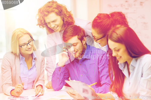 Image of creative team with papers and clipboard at office