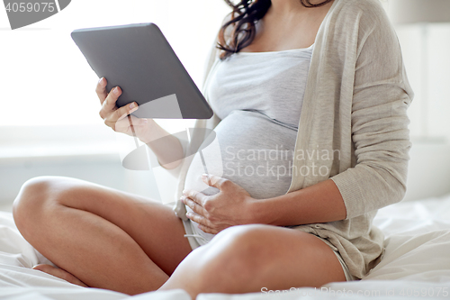 Image of close up of pregnant woman with tablet pc at home