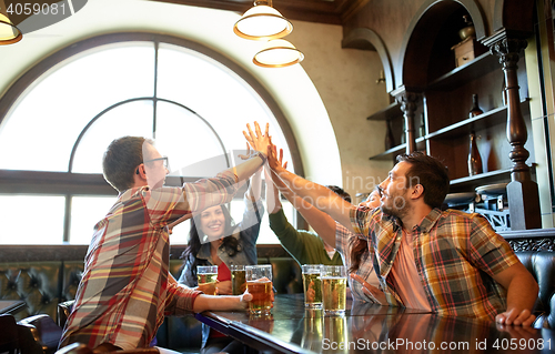 Image of friends with beer making high five at bar or pub
