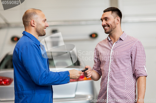 Image of auto mechanic giving key to man at car shop
