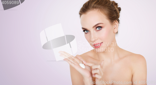 Image of happy young woman with moisturizing cream on hand