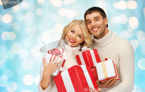 Image of happy couple in sweaters holding christmas gifts