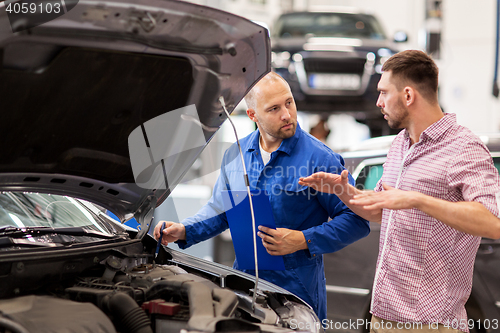 Image of auto mechanic with clipboard and man at car shop