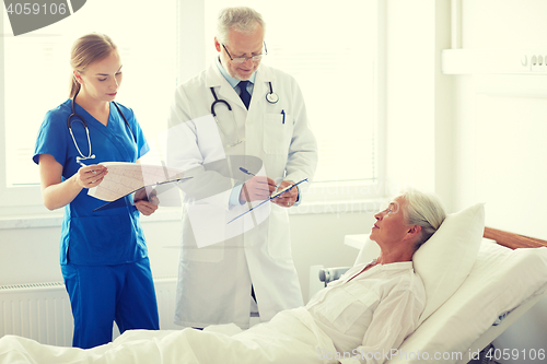 Image of doctor and nurse visiting senior woman at hospital