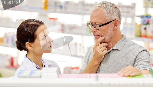 Image of pharmacist showing drug to senior man at pharmacy