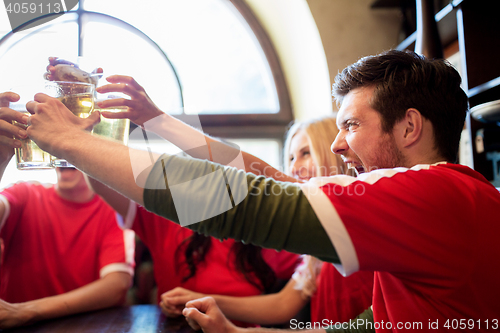 Image of football fans clinking beer glasses at sport bar