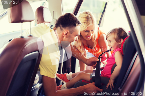 Image of happy parents fastening child with car seat belt