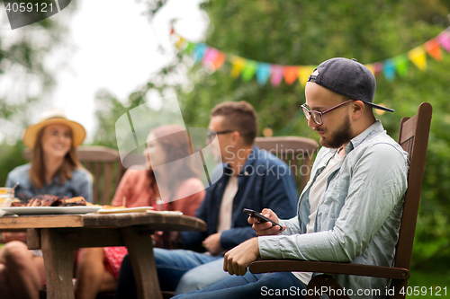 Image of man with smartphone and friends at summer party