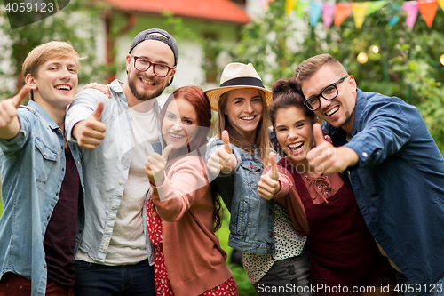 Image of happy friends showing thumbs up at summer garden