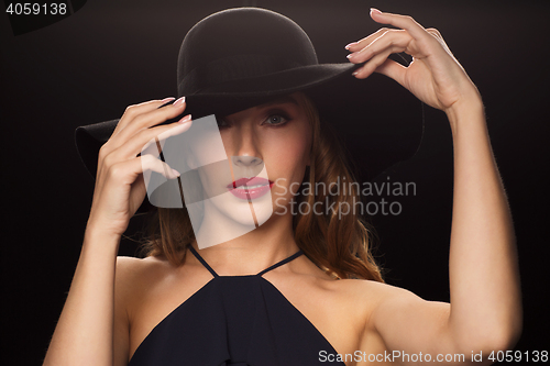 Image of beautiful woman in black hat over dark background