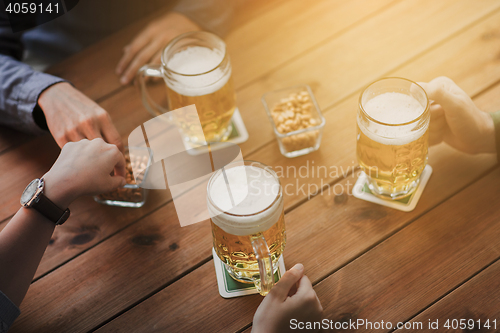 Image of close up of hands with beer mugs at bar or pub