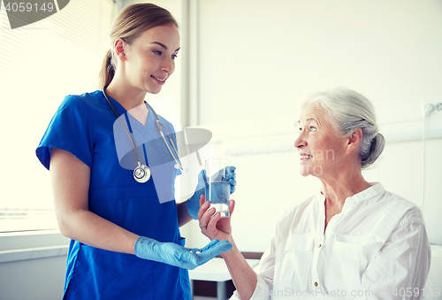 Image of nurse giving medicine to senior woman at hospital