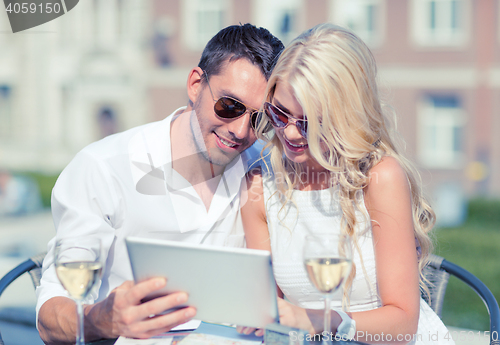 Image of couple looking at tablet pc in cafe