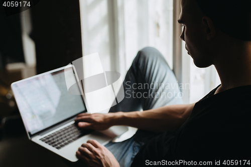 Image of Young man typing something on a laptop