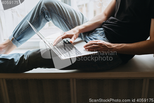 Image of Young man typing something on a laptop