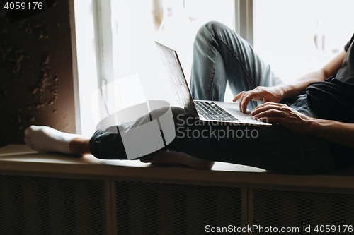 Image of Young man typing something on a laptop