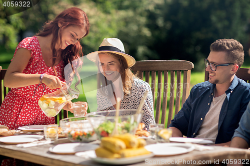 Image of happy friends having dinner at summer garden party