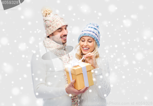 Image of smiling couple in winter clothes with gift box