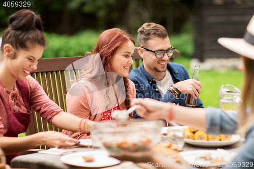 Image of happy friends having dinner at summer garden party