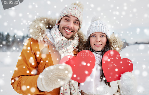 Image of happy couple with red hearts over winter landscape