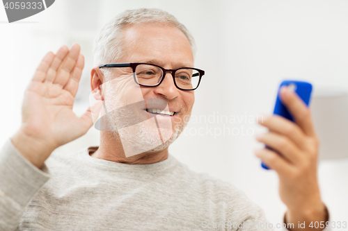 Image of senior man having video call on smartphone at home